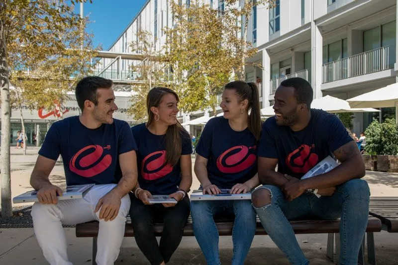 Estudiantes con la camiseta de Fem Esports URV sentados en el campus
