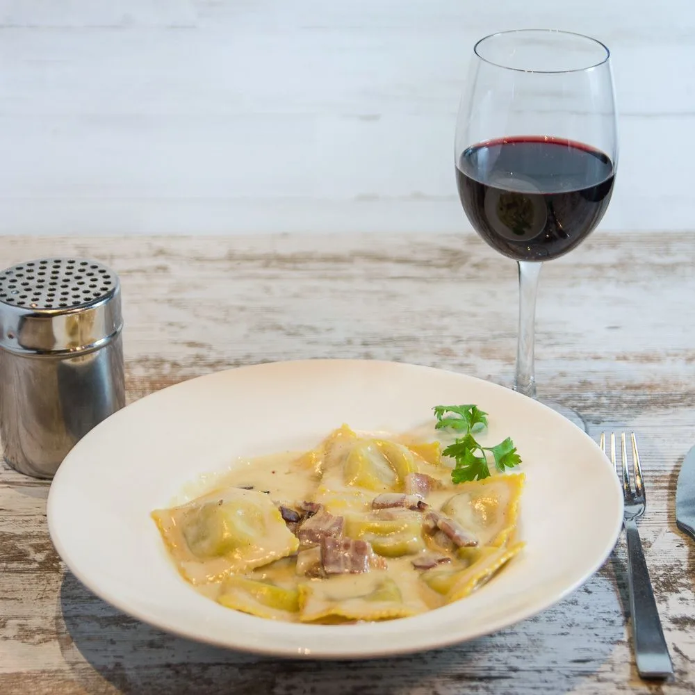 Plato de pasta rellena con copa de vino tinto