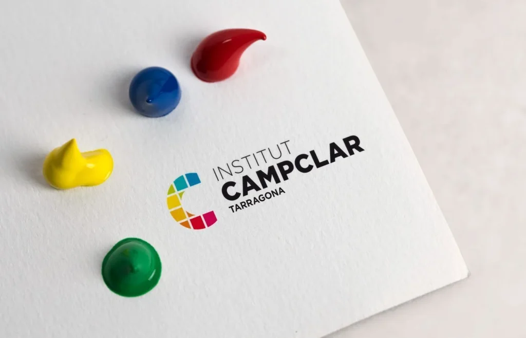 Logotipo del Institut Campclar impreso sobre papel, junto a gotas de pintura de colores