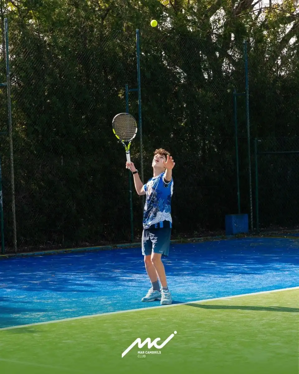 Niño sacando en la pista de tenis del club